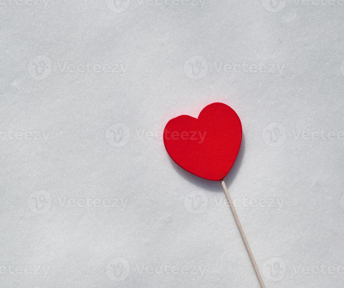 coeur rouge sur un bâton se trouve sur la neige blanche photo