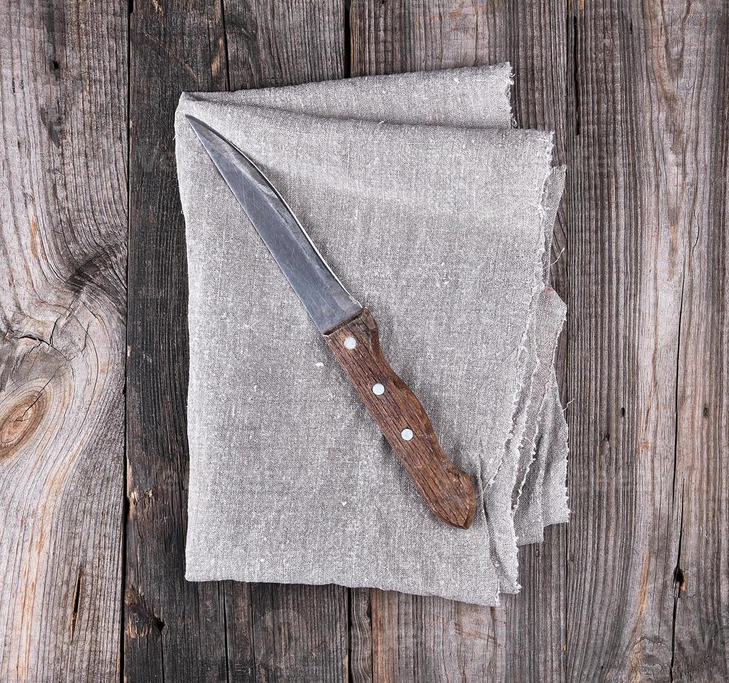 vieux couteau de cuisine sur une serviette grise, fond en bois photo