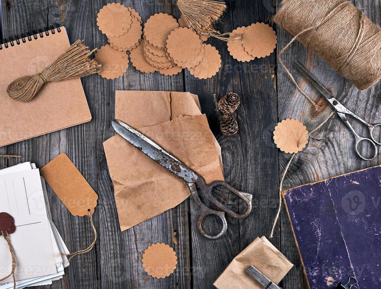 bobine de corde marron, étiquettes en papier et vieux ciseaux sur fond de bois gris photo