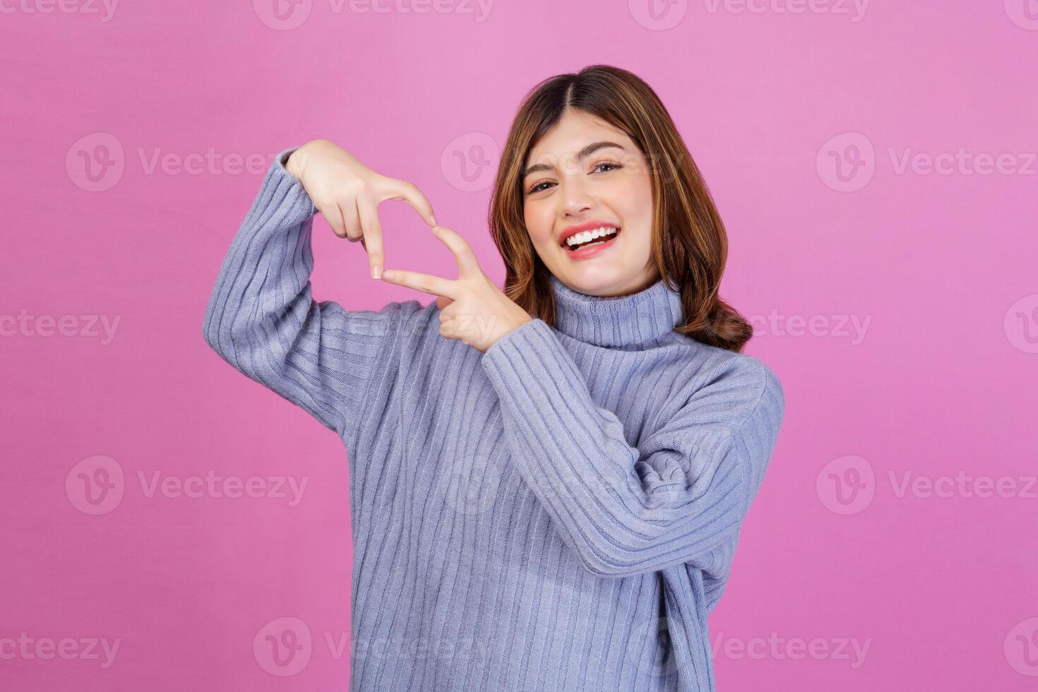 portrait d'une jeune femme souriante se sent heureuse et romantique formes coeur geste isolé sur fond rose photo