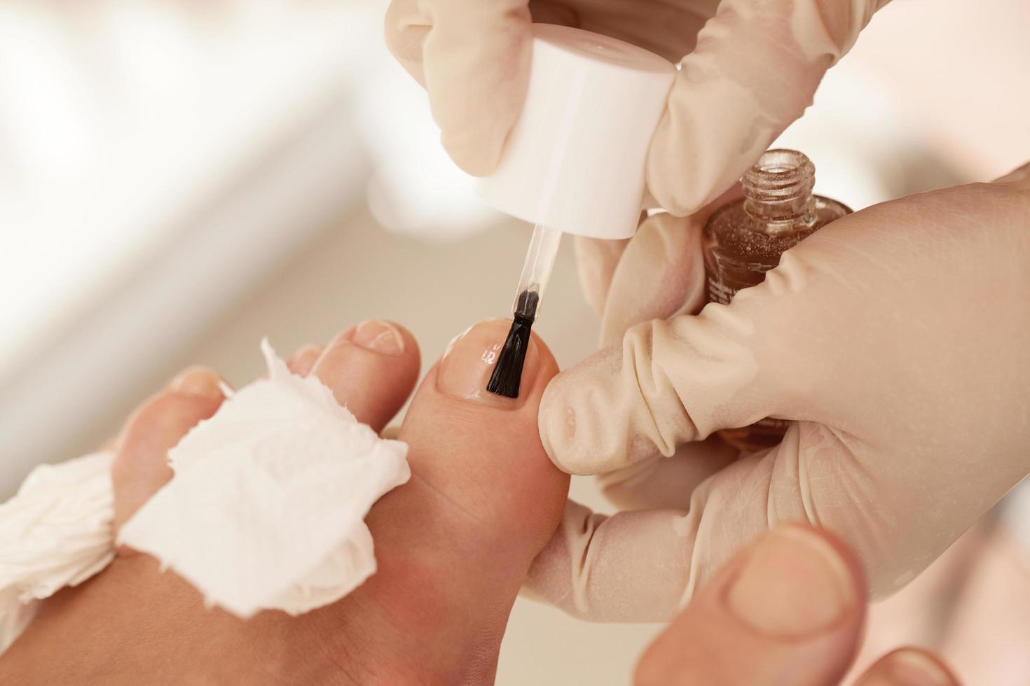 appliquer du vernis à ongles pendant la pédicure au spa de beauté photo