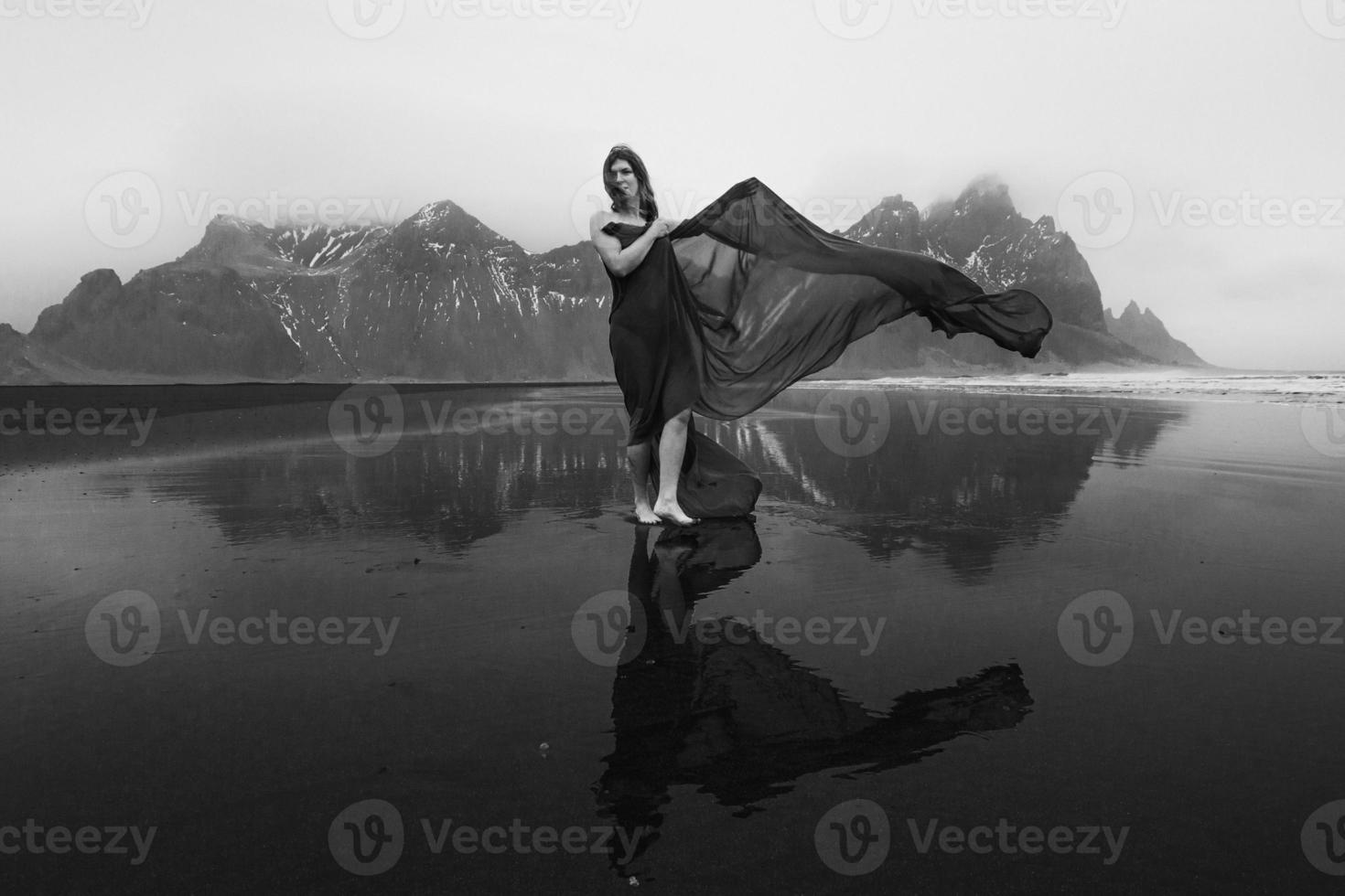 Dame avec une longue cape en mousseline de soie sur la plage de la mer photographie panoramique monochrome photo