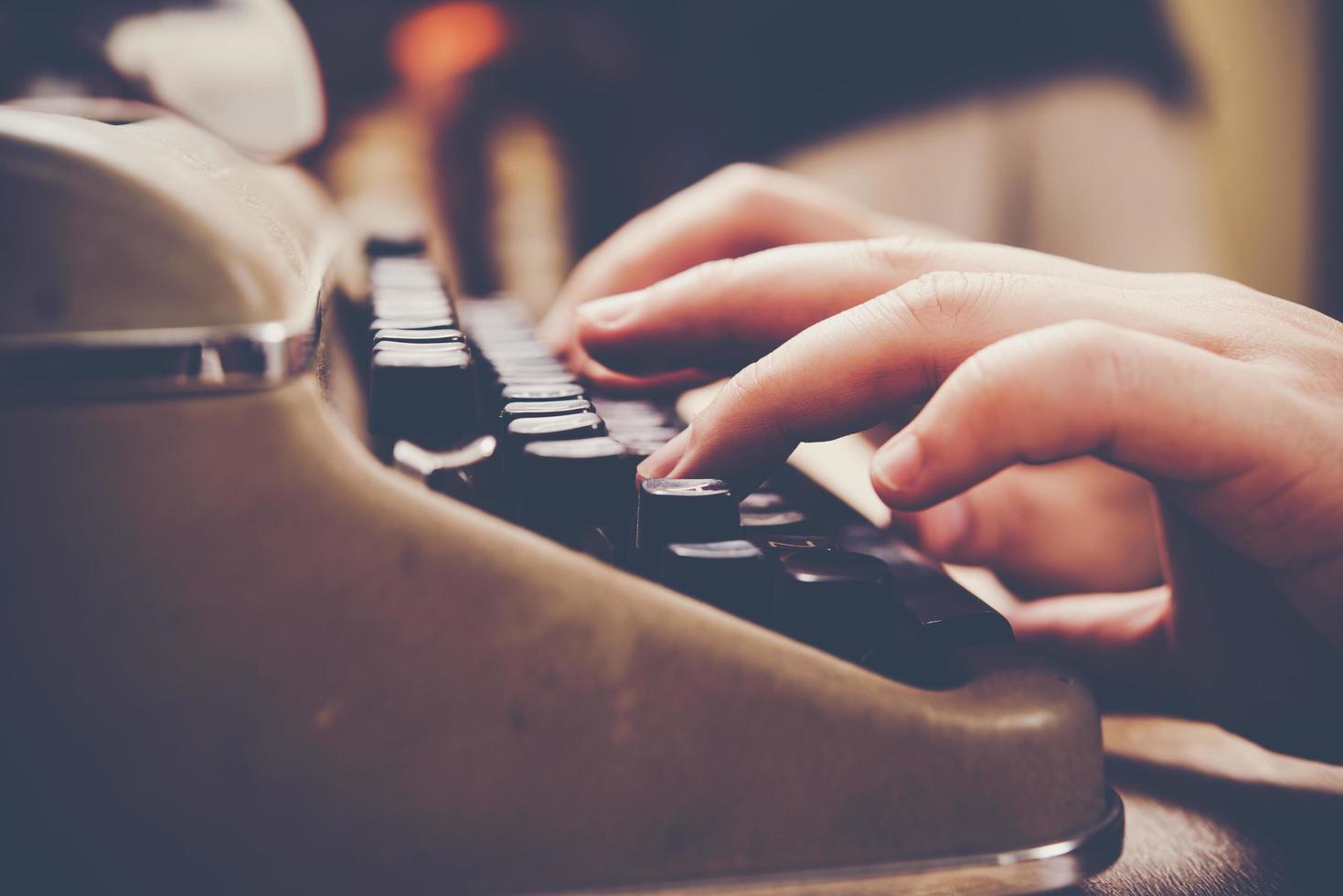 mains tapant sur machine à écrire vintage sur table en bois photo