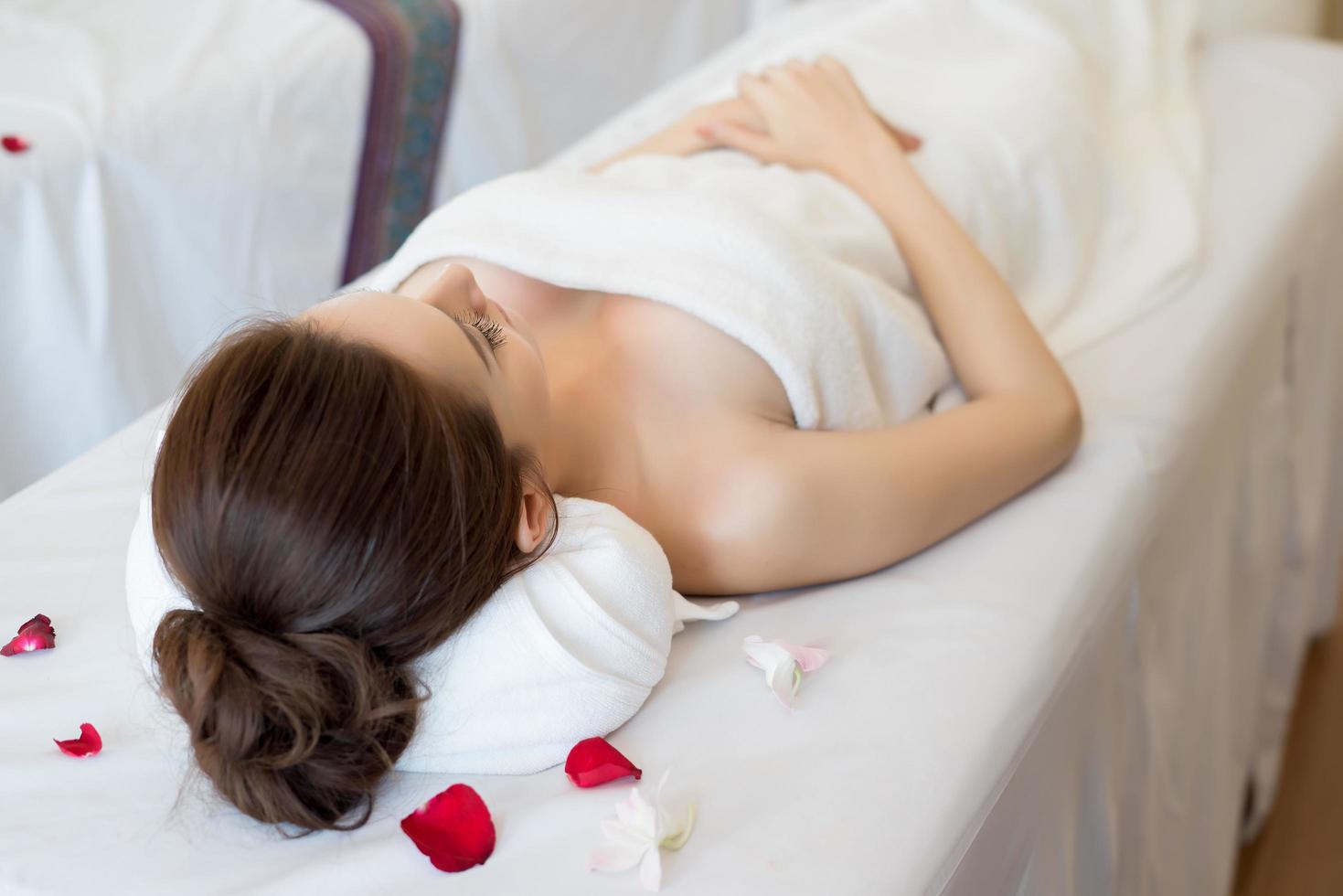 belle femme souriante avec des fleurs au repos dans le spa avant le massage photo