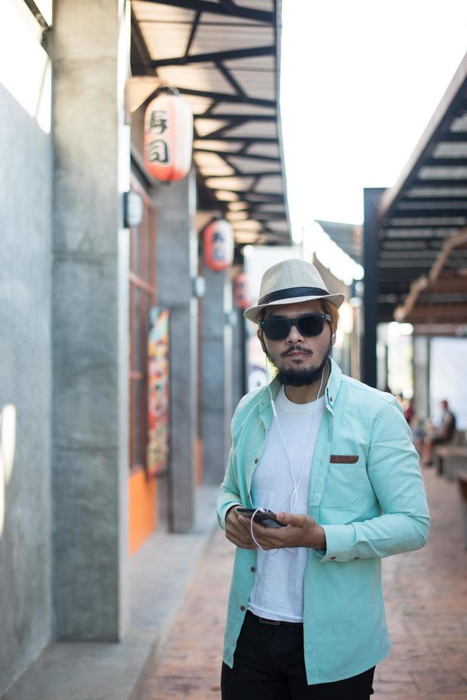 homme hipster, écouter de la musique avec son smartphone dans la rue photo