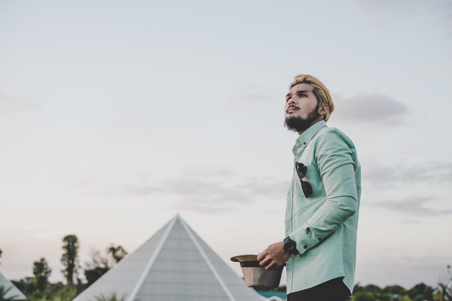 jeune homme hipster debout dans le parc avec ciel à la recherche de suite. photo