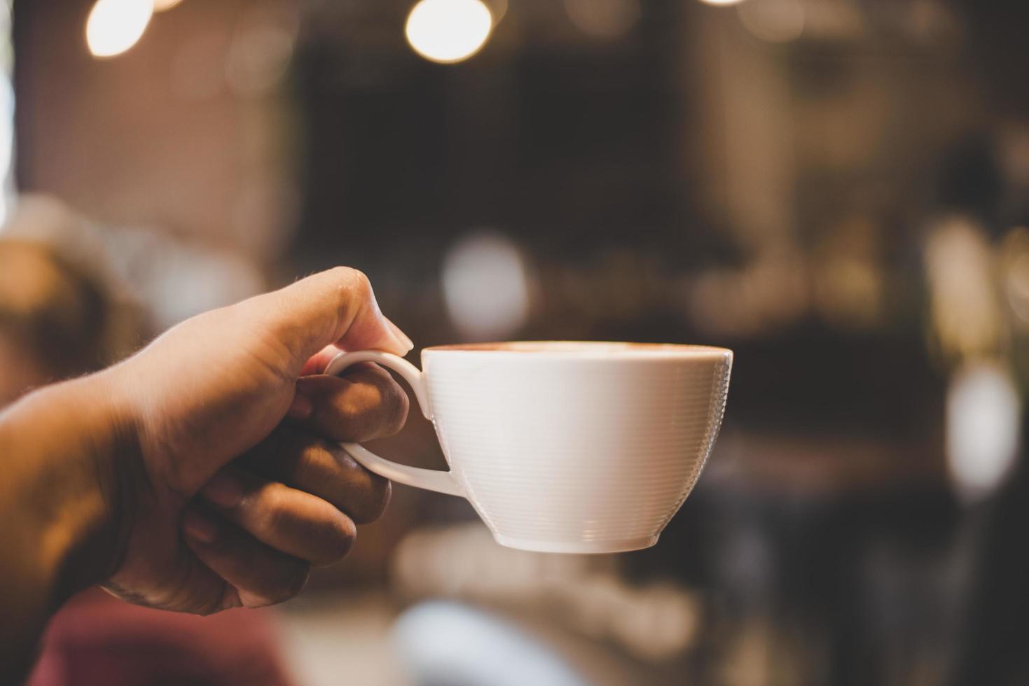 mains tenant une tasse de café dans un café avec filtre vintage photo