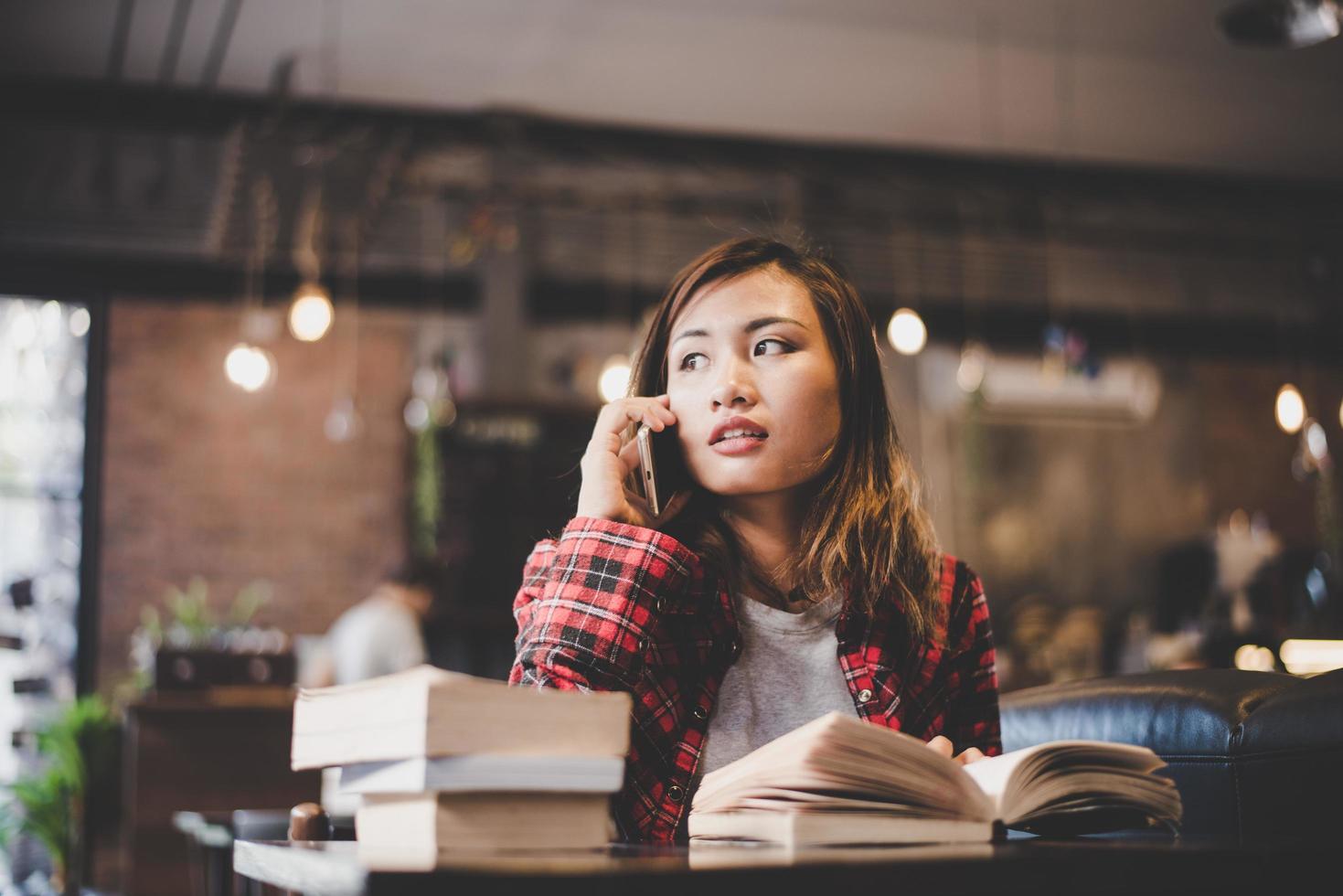 adolescent hipster assis et lisant un livre dans un café photo