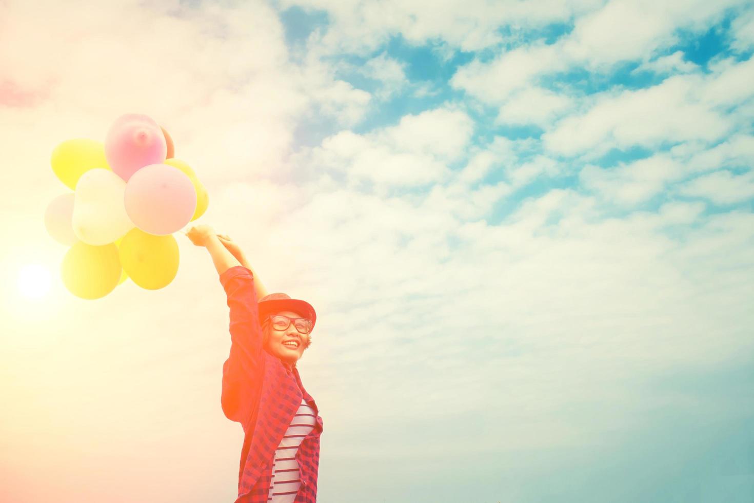 Belle jeune femme appréciant des ballons multicolores dans le ciel lumineux photo