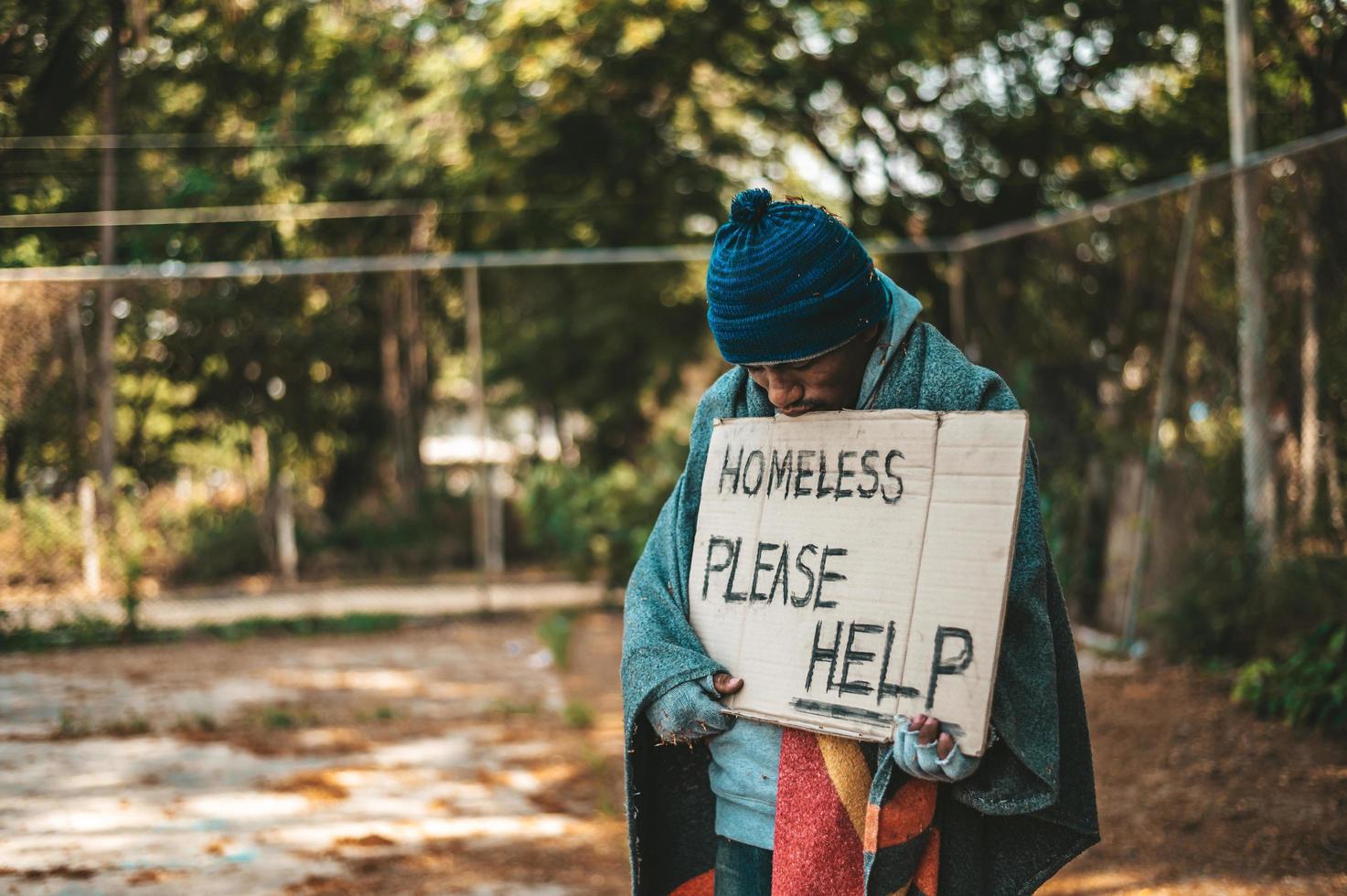 Le mendiant se tient dans la rue avec un signe d'aide photo
