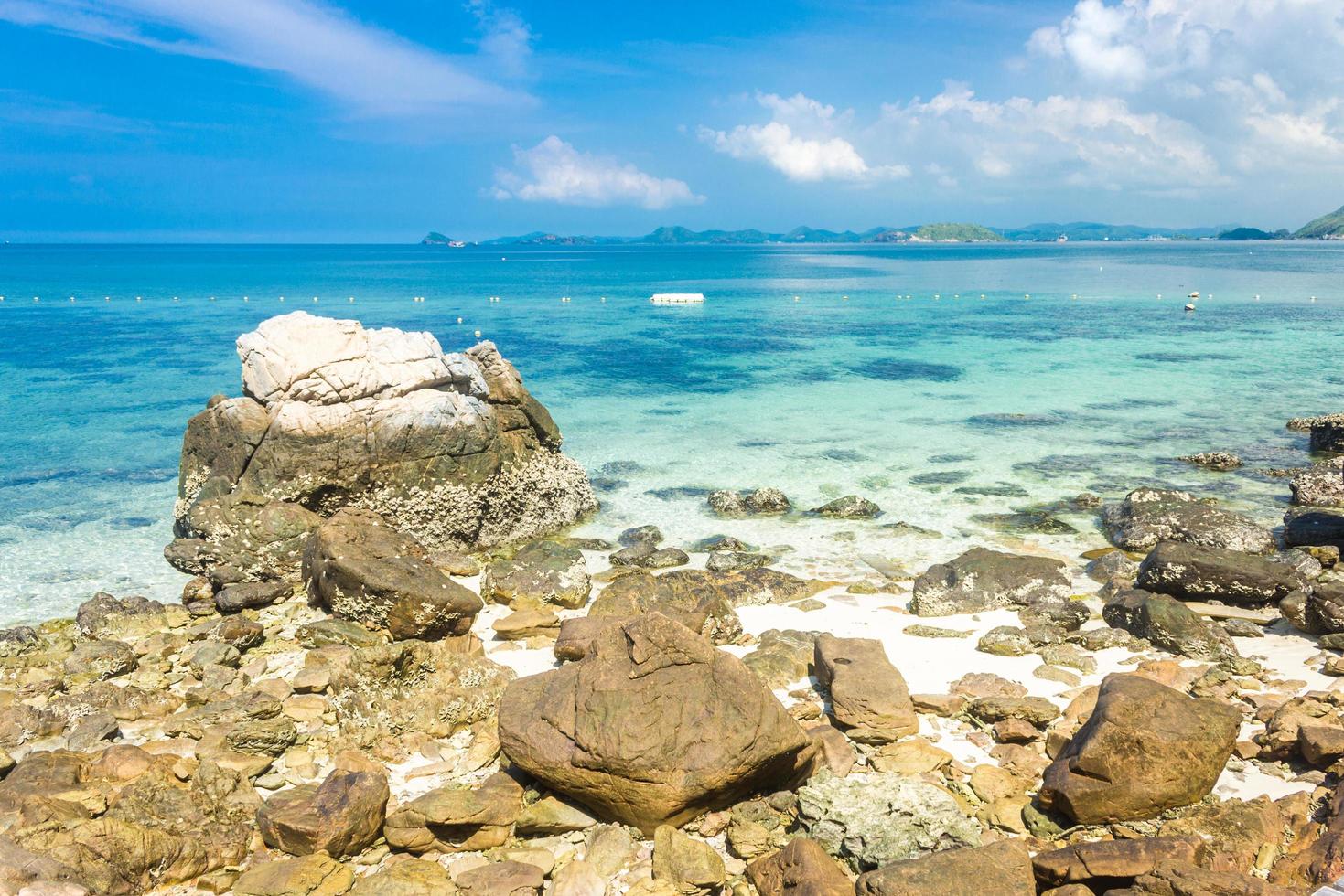 île tropicale rock sur la plage avec eau bleu clair et ciel bleu nuageux. photo