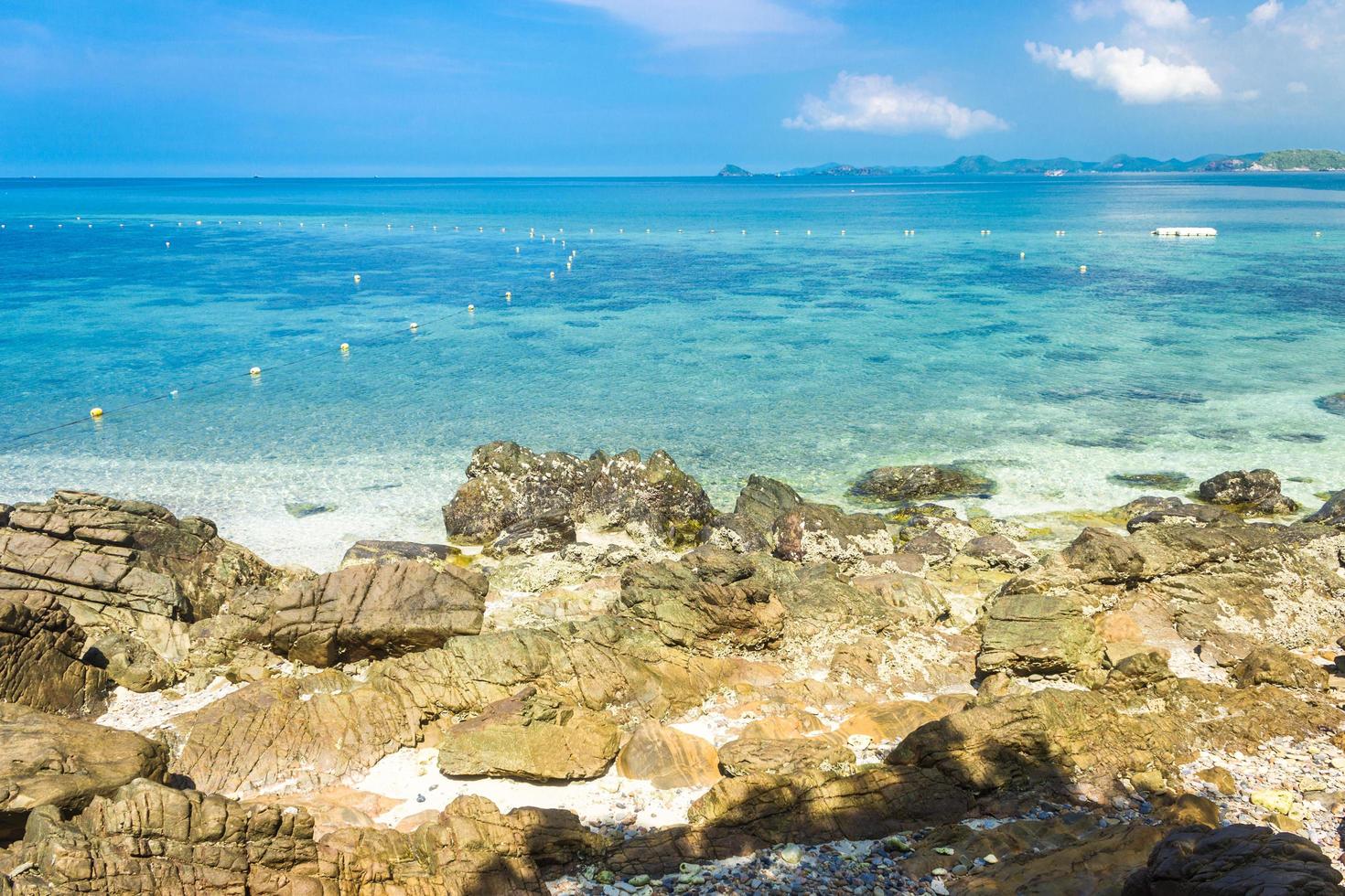 île tropicale rock sur la plage avec de l'eau bleu clair et ciel bleu nuageux photo