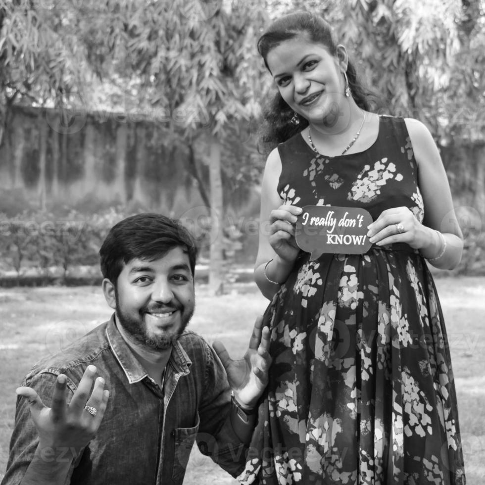 couple indien posant pour une séance photo de maternité. le couple pose dans une pelouse avec de l'herbe verte et la femme étale sa bosse de bébé dans le jardin de lodhi à new delhi, inde - noir et blanc