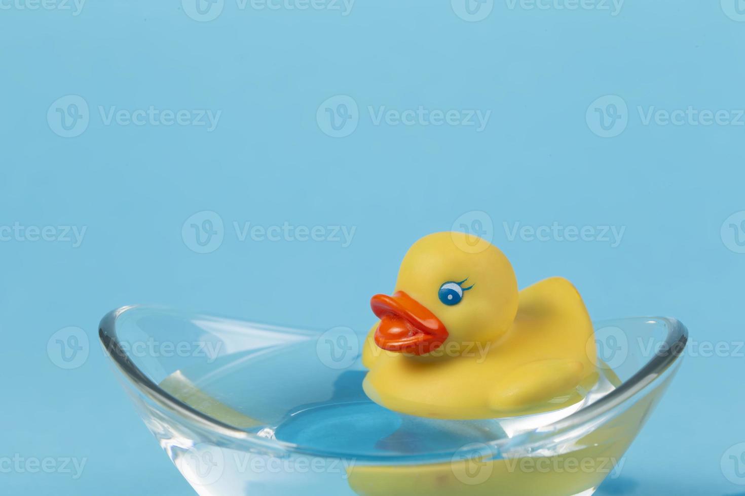 un canard en caoutchouc jaune flotte dans un bain sur fond bleu. photo