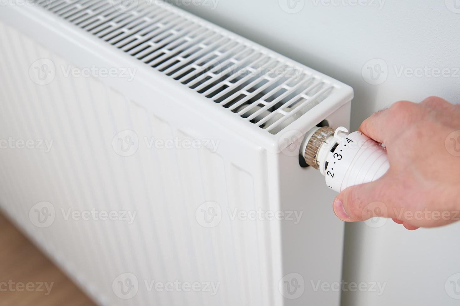 Tourner à la main le thermostat du bouton du radiateur de chaleur photo