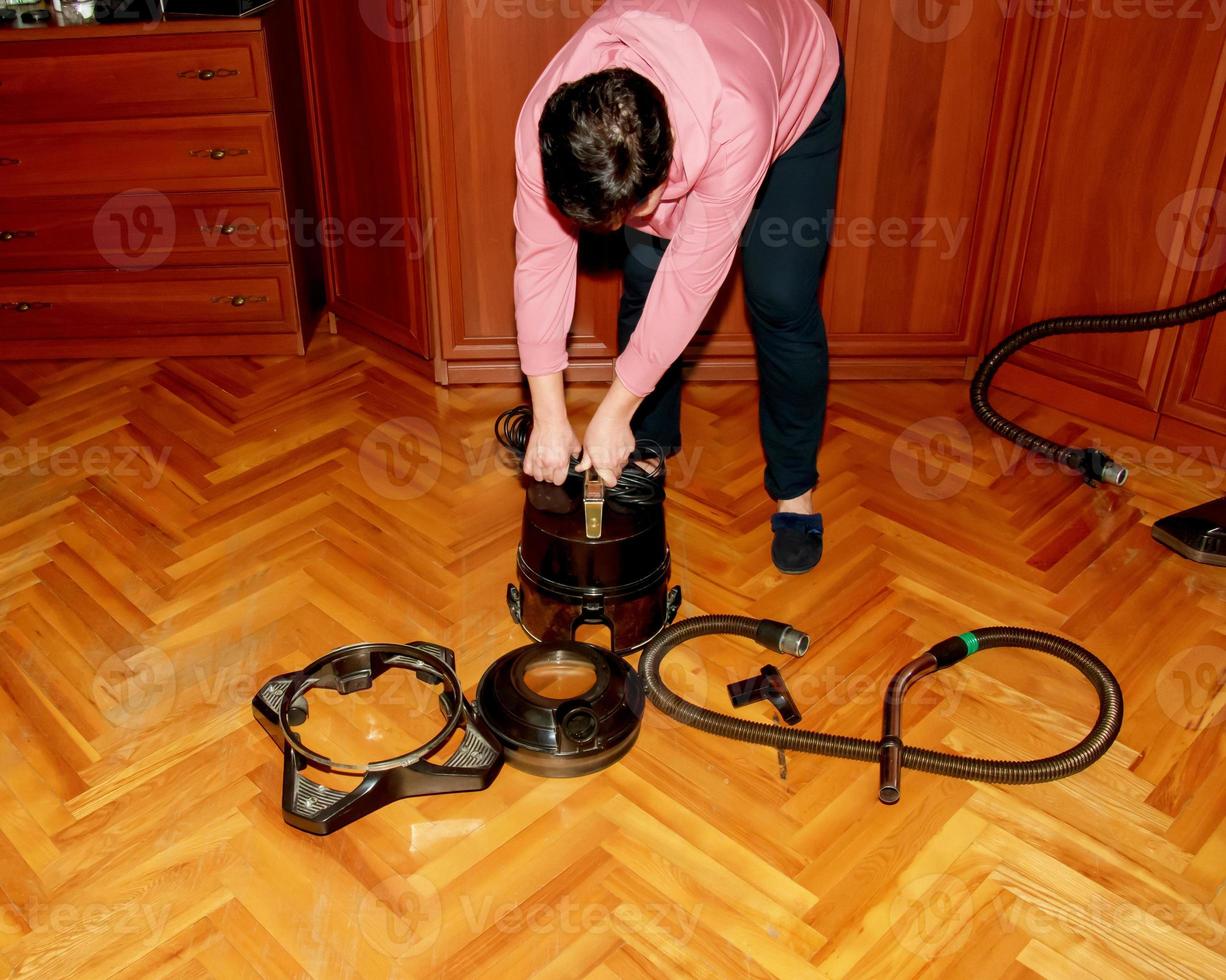 une femme d'âge moyen récupère un aspirateur pour le nettoyage de la maison. photo