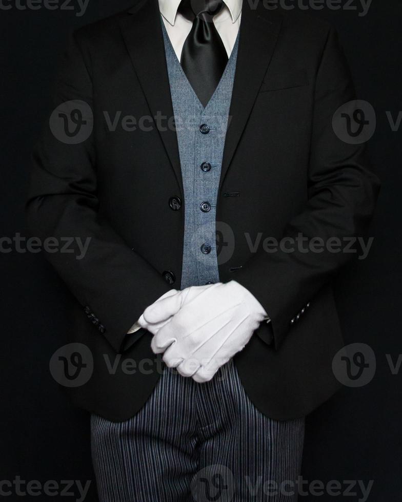 majordome en costume sombre et gants blancs debout à l'attention digne. concept d'industrie de services et d'hospitalité professionnelle. photo