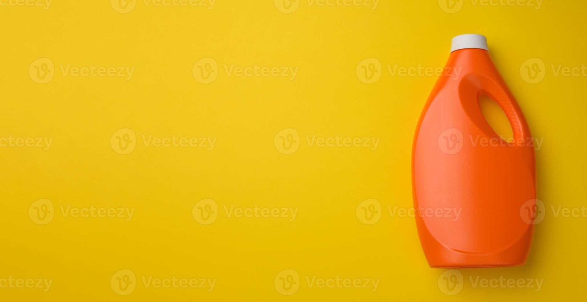 bouteille en plastique orange pour lessive liquide sur fond jaune, vue de dessus photo