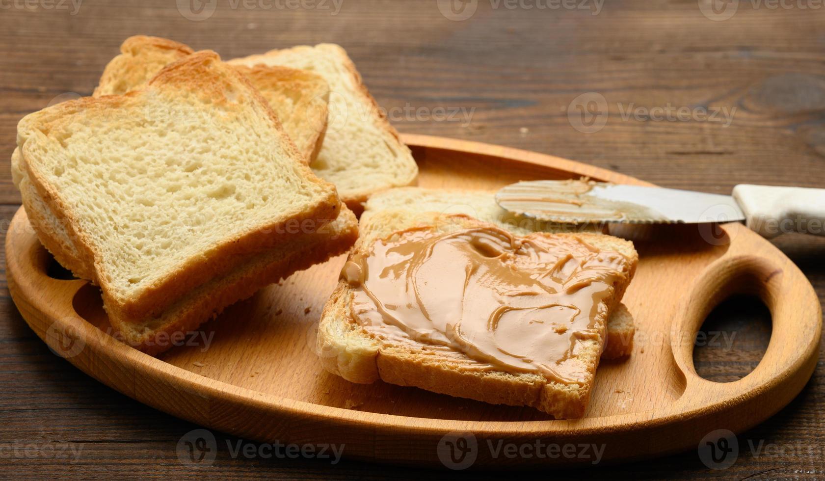 beurre d'arachide sur une tranche carrée de farine de blé blanc, petit-déjeuner photo