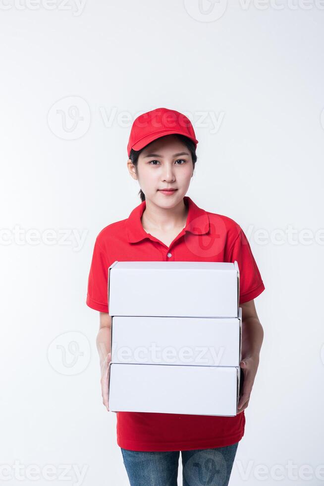 image d'un jeune livreur conscient en casquette rouge t-shirt blanc uniforme masque facial gants debout avec boîte en carton blanc vide isolé sur fond gris clair studio photo