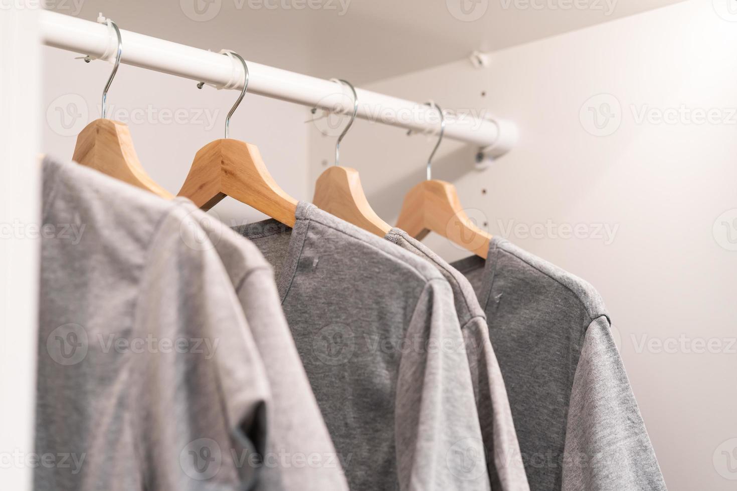 vêtements gris sur porte-vêtements. t-shirt gris à porter sur des cintres dans un placard ou un concept de nettoyage de printemps. garde-robe de maison d'été. vêtements suspendus sur un porte-vêtements dans un magasin ou un placard à domicile. photo