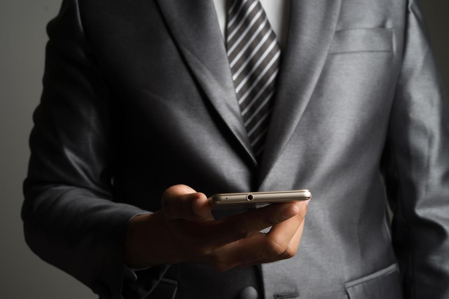 Portrait of businessman holding smartphone sur fond noir photo