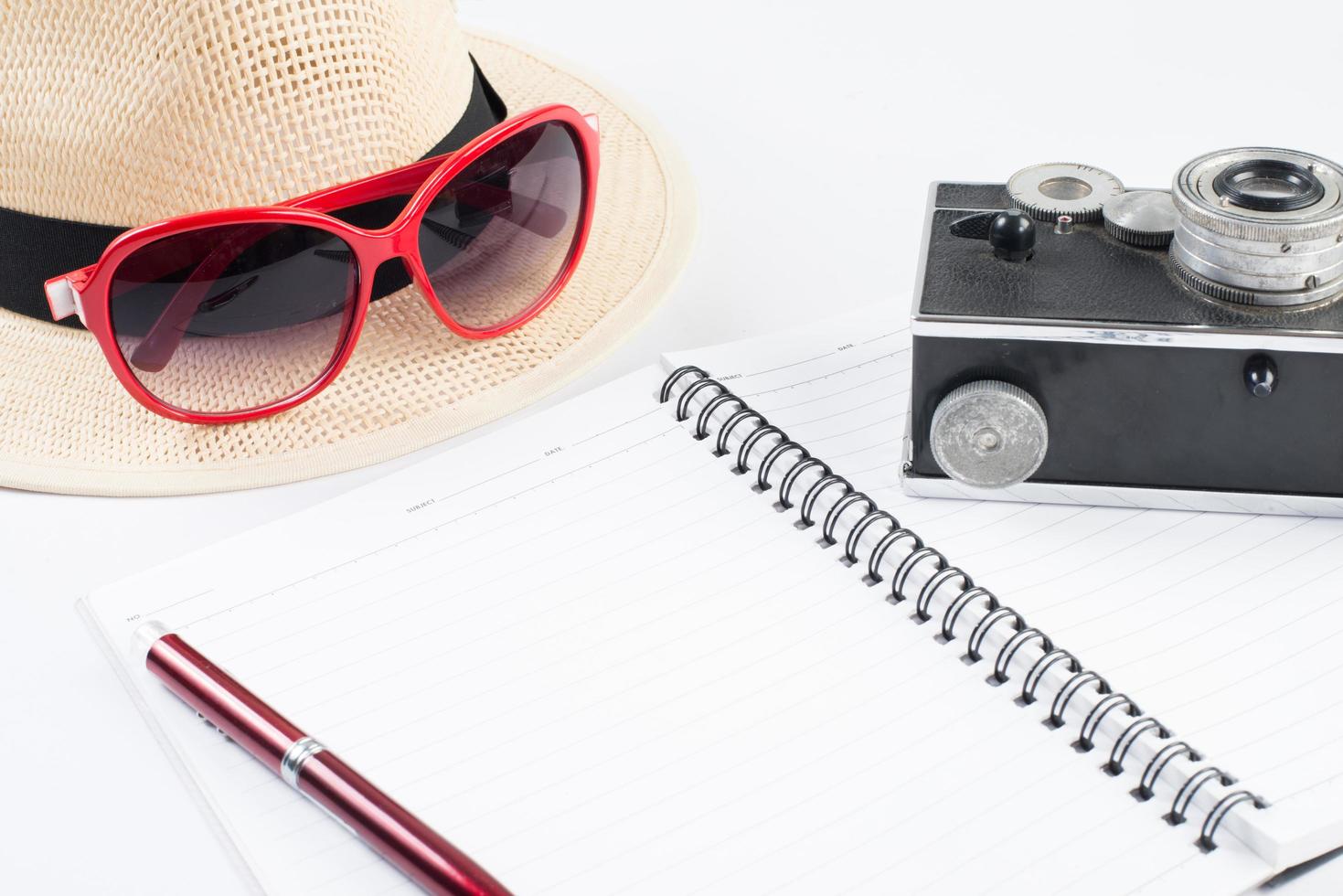 chapeau, lunettes de soleil et appareil photo vintage avec bloc-notes isolé sur fond blanc