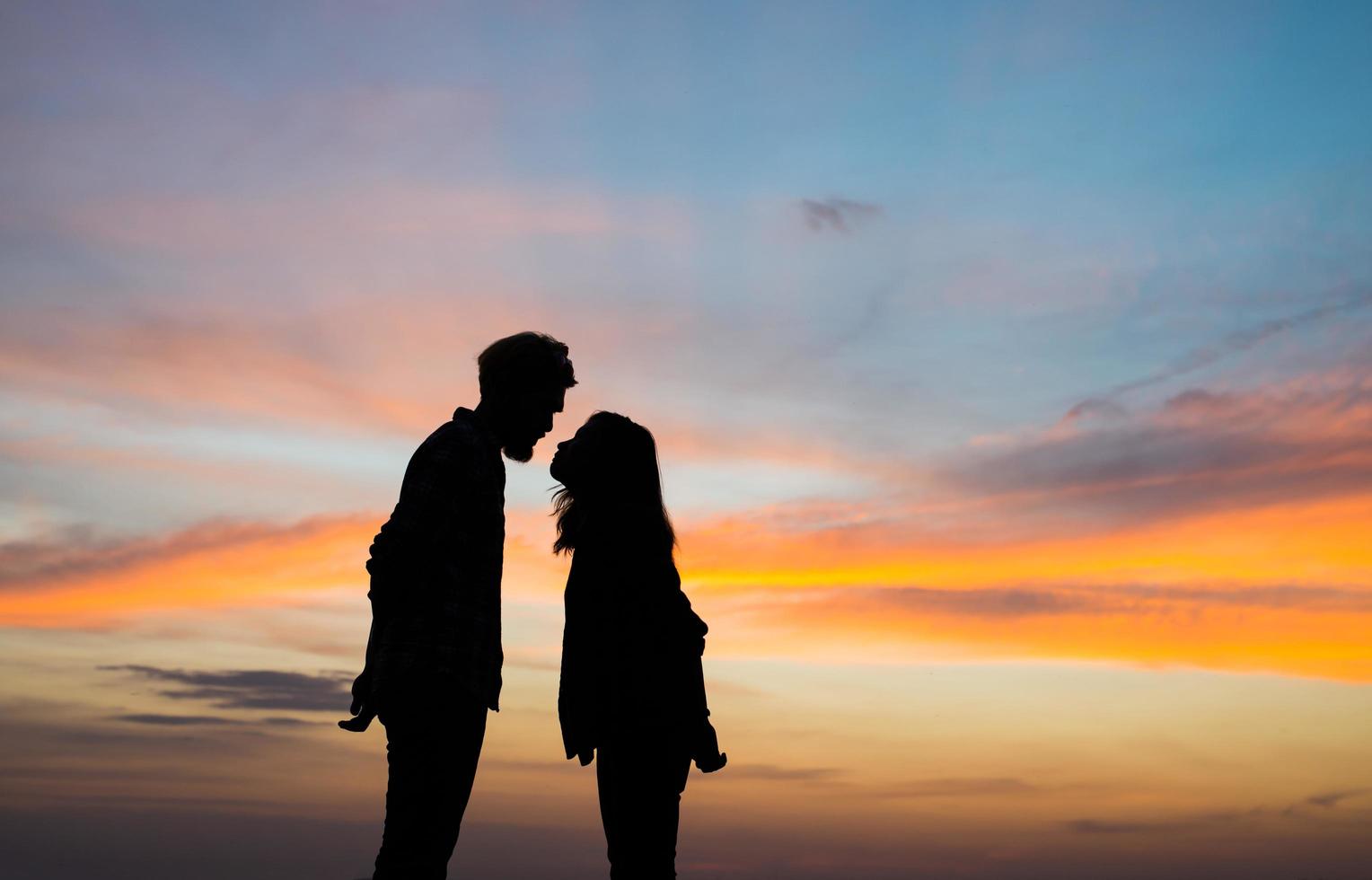 silhouette de jeune couple ensemble pendant le coucher du soleil photo