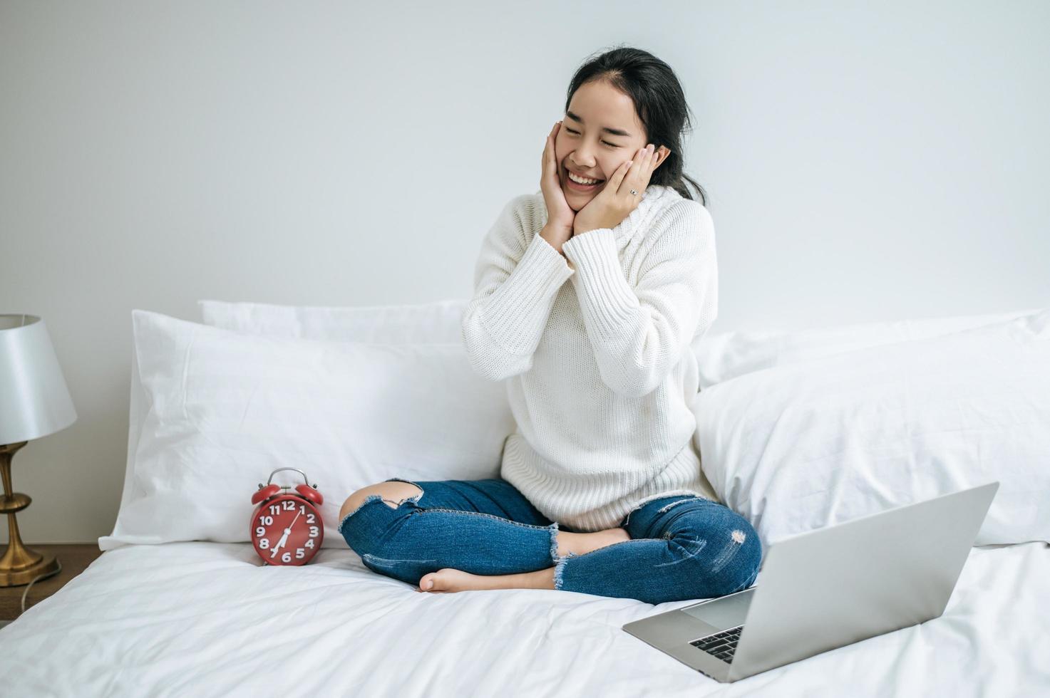 jeune femme assise sur son lit souriant joyeusement photo