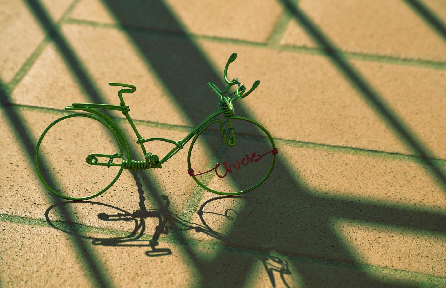 Vélo fil miniature vert avec des ombres sur la chaussée en béton photo