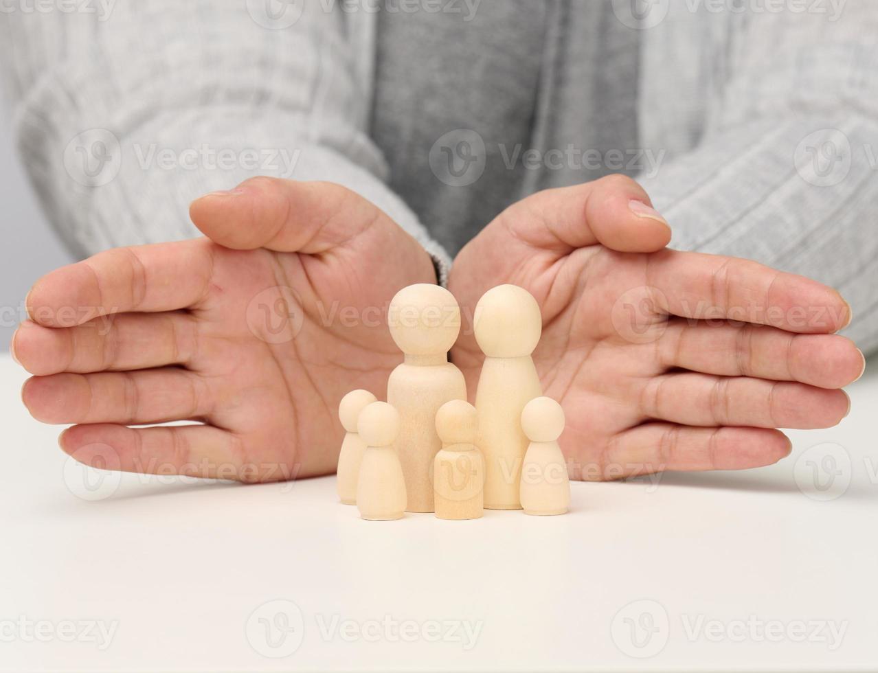 en bois figurines de Hommes, une famille gardé par deux femelle mains. aider, la vie assurance, sécurité photo
