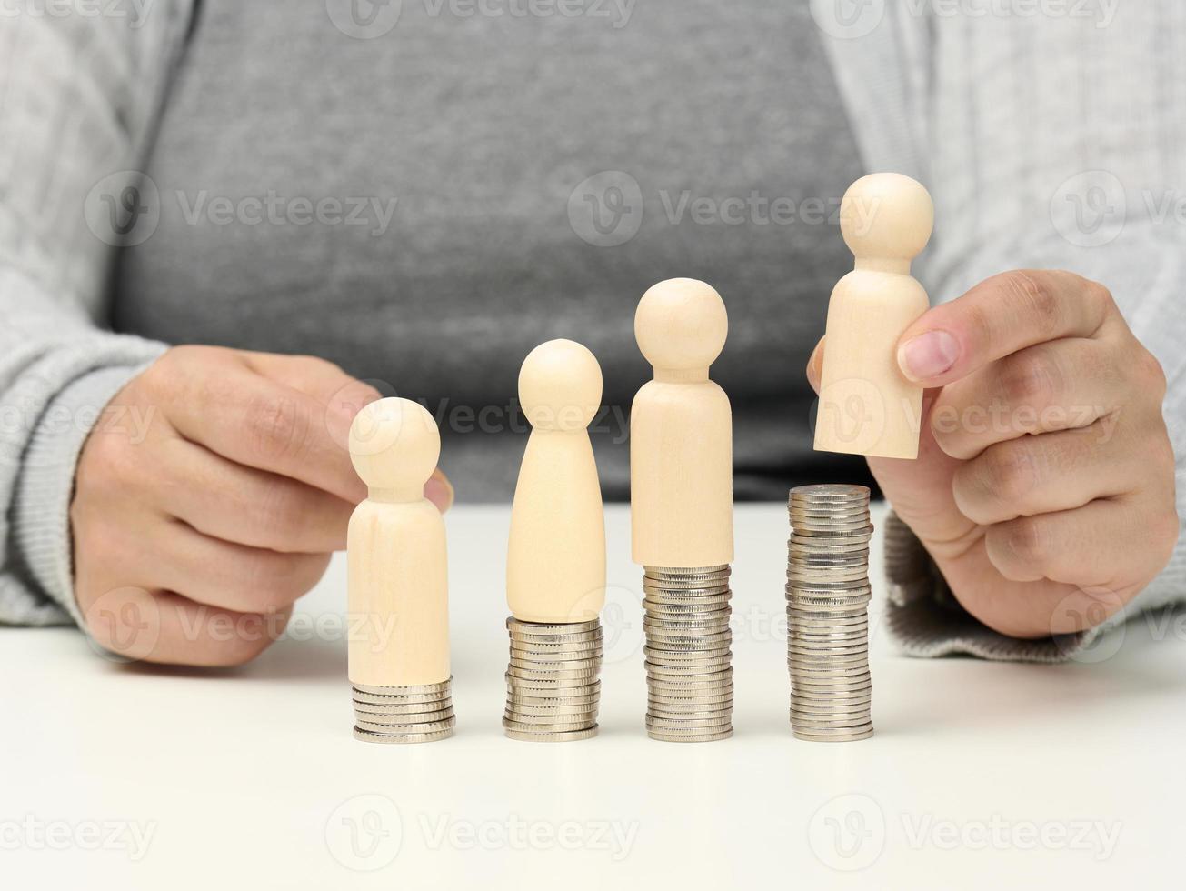 en bois Les figures de Hommes supporter sur piles de pièces de monnaie, une blanc tableau. employé mentorat et croissance concept, le revenu et un salaire croissance photo