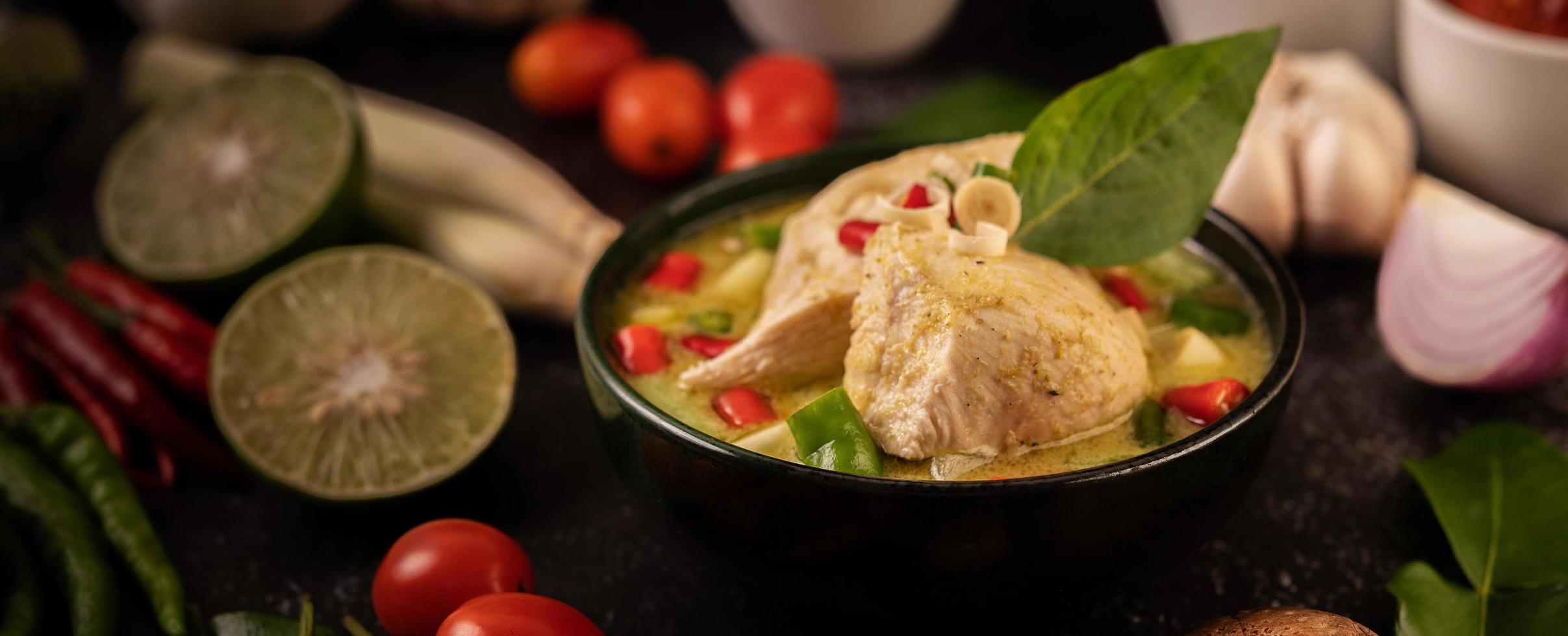 plat de curry vert avec poulet, chili et basilic et tomate et citron vert photo