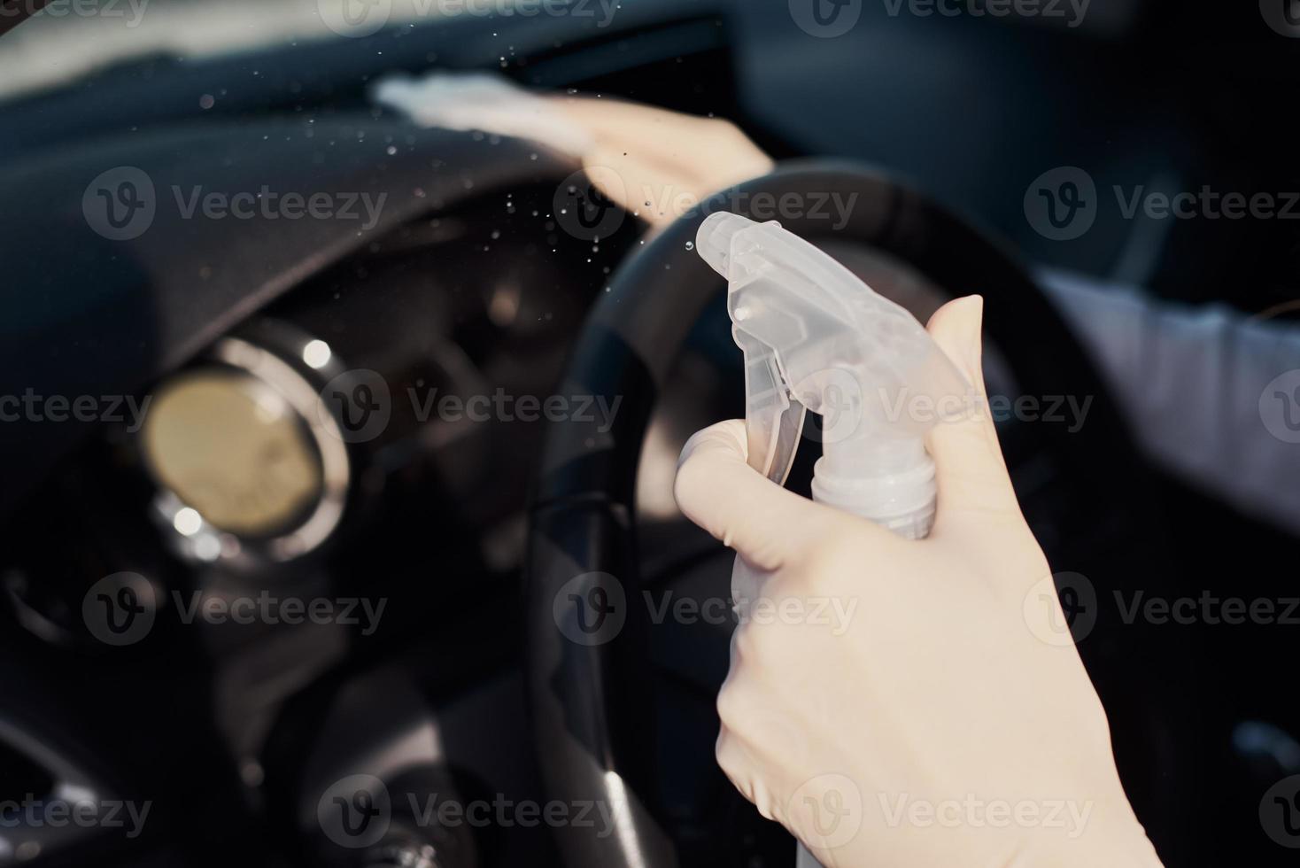 femme nettoyant une voiture avec un spray désinfectant pour se