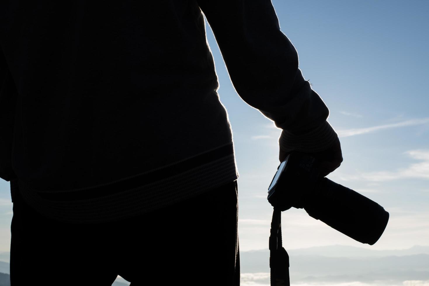 silhouette de jeune photographe tenant un appareil photo avec paysage de montagne