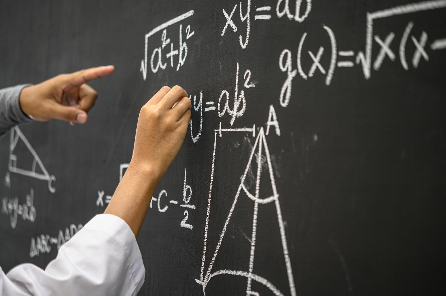 étudiant à la craie blanche montrant la formule sur le tableau noir photo