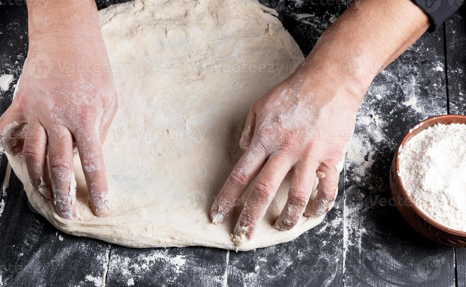 Pour des hommes mains pétrir une rond pièce de pâte photo