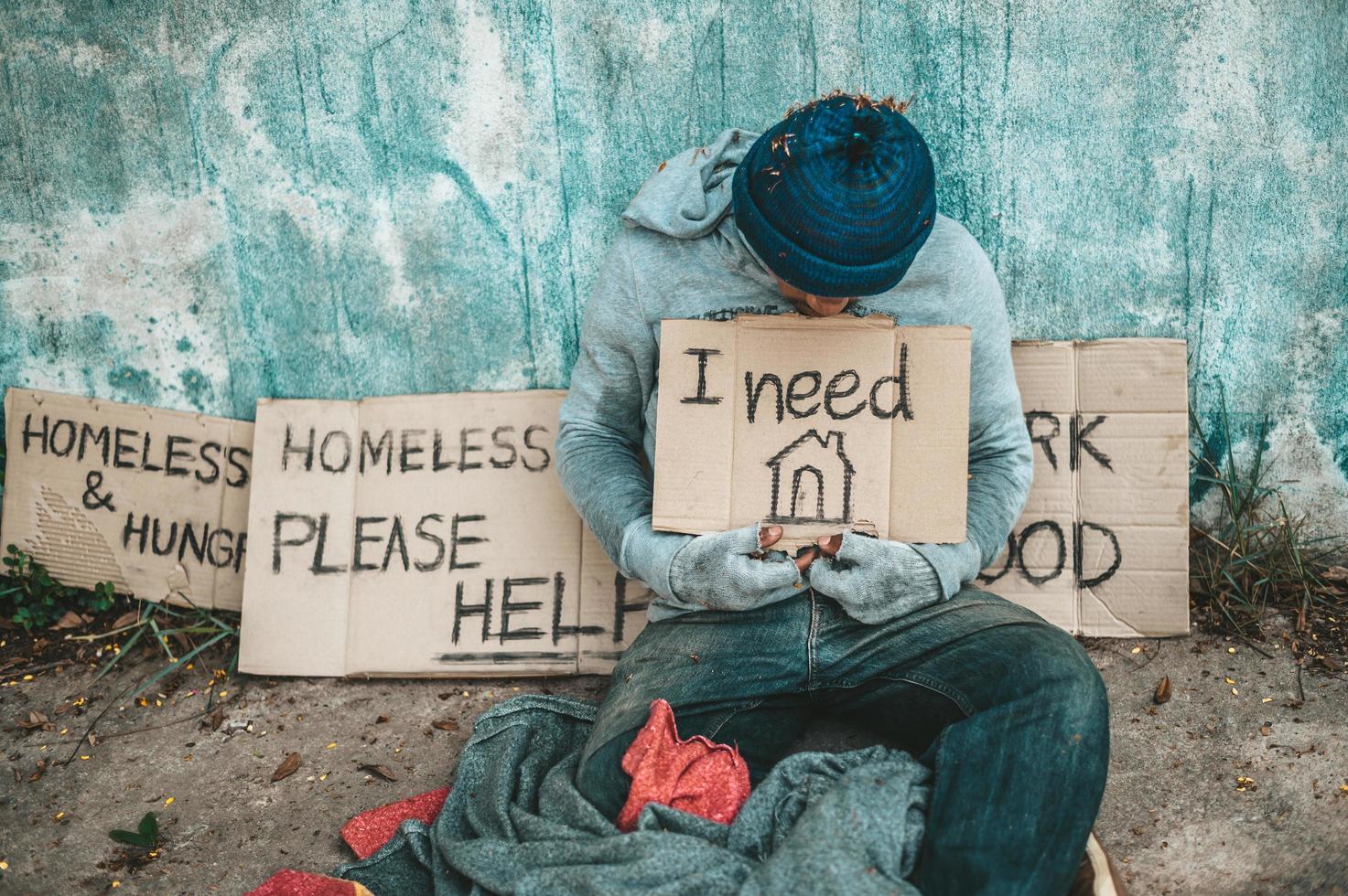 l'homme est assis à côté de la rue avec un message aux sans-abri photo