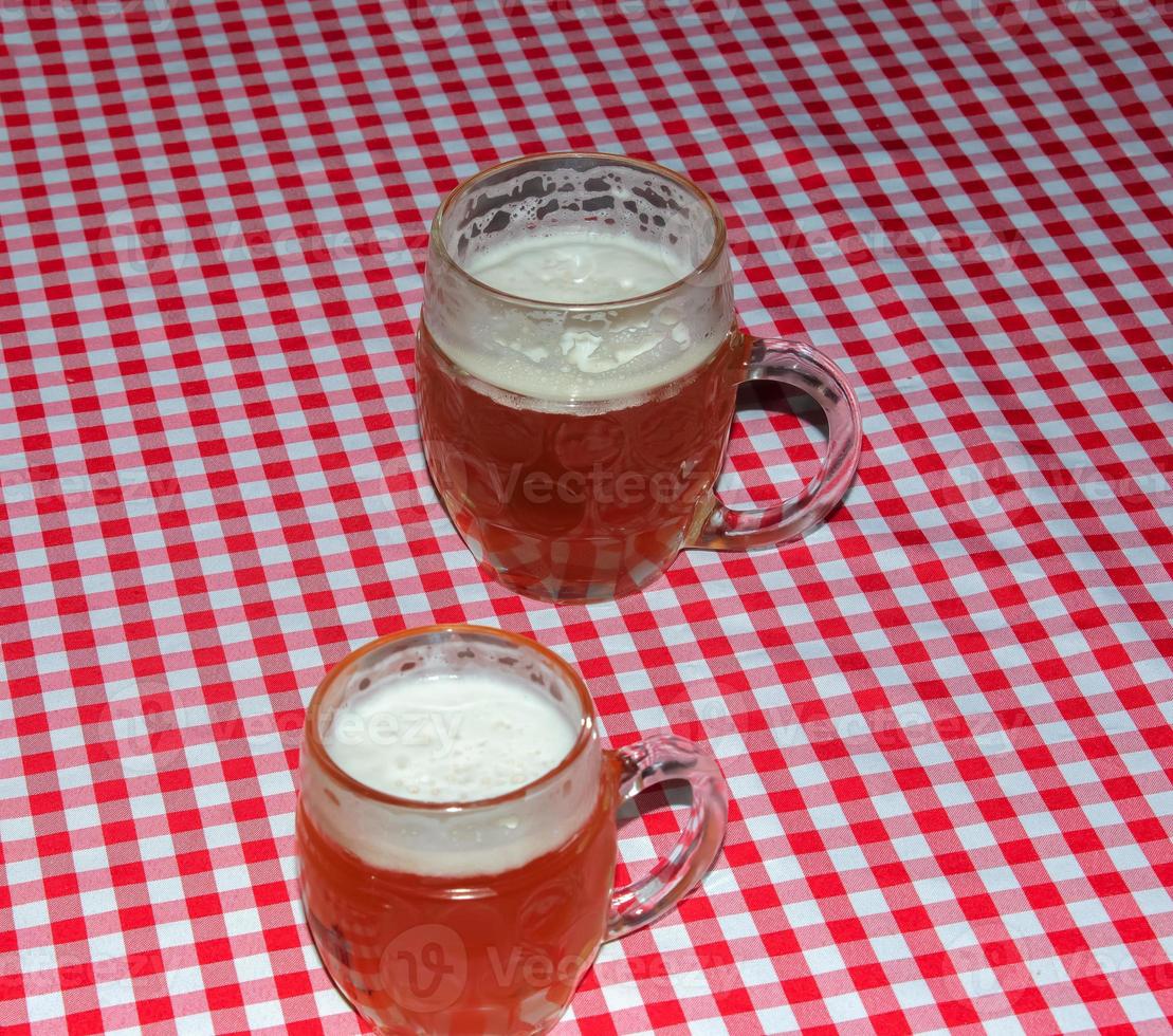 une chope de bière sur une table recouverte d'une nappe à carreaux rouge. photo