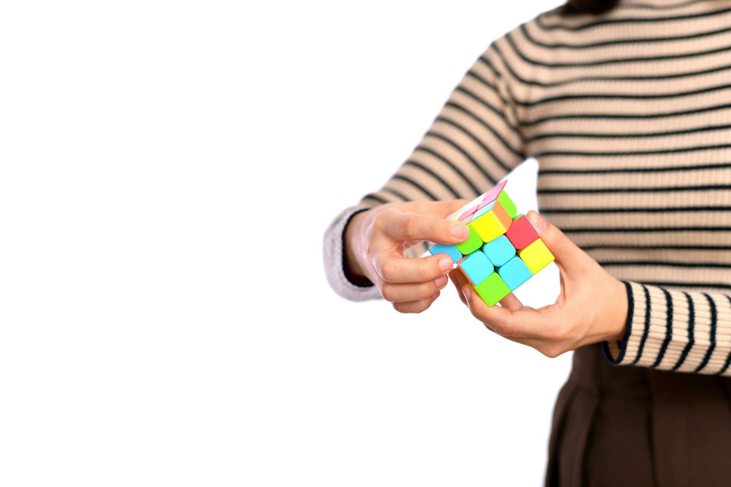 femelle mains en portant une Rubik cube permanent sur blanc Contexte photo