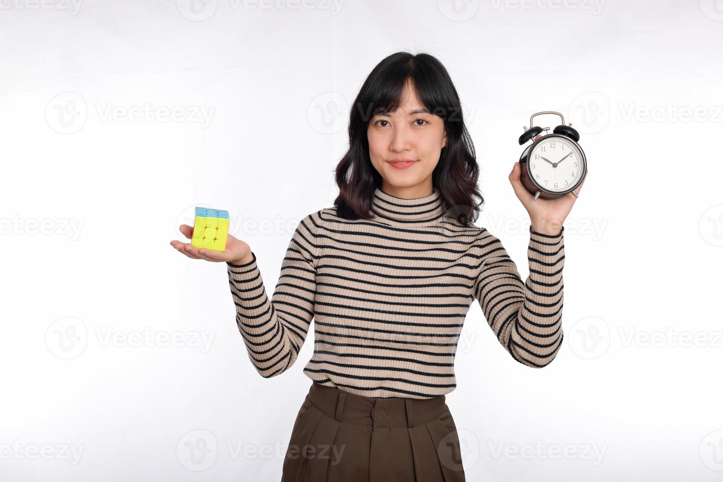 asiatique femme en portant alarme l'horloge et Rubik cube permanent sur blanc Contexte. résolution cubique problèmes, problème Solution et fabrication stratégique se déplace concept photo