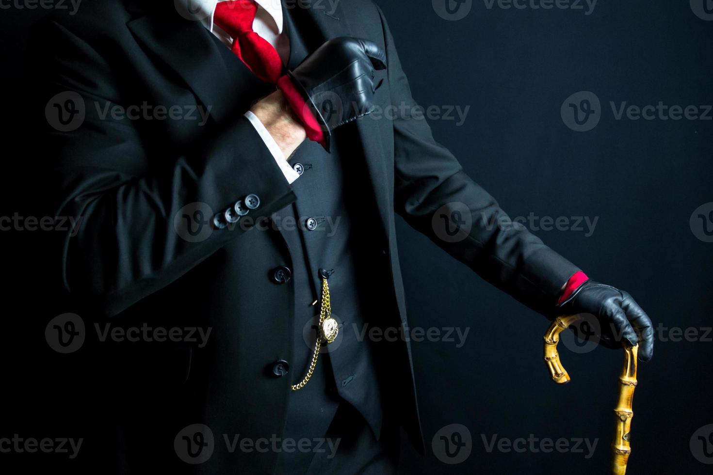 portrait de élégant gentilhomme dans noir costume et cuir gants penché sur parapluie sur noir Contexte. ancien style et rétro mode. photo