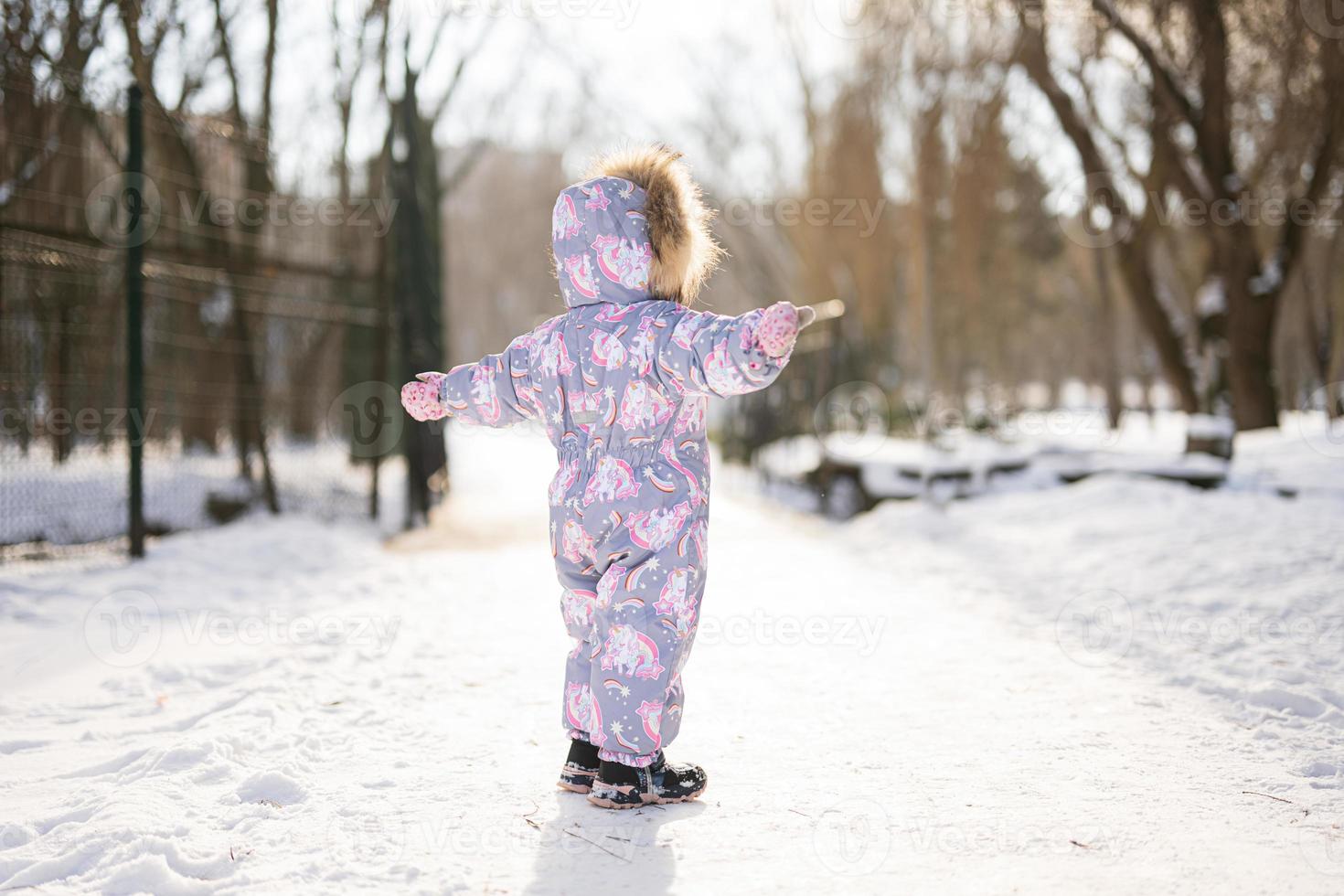 retour de bébé fille porter enfant combinaison de ski sur une ensoleillé glacial hiver journée. photo