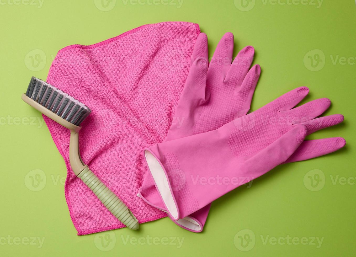 rose tapis, caoutchouc gants pour nettoyage, brosses sur une vert arrière-plan, plat poser. photo