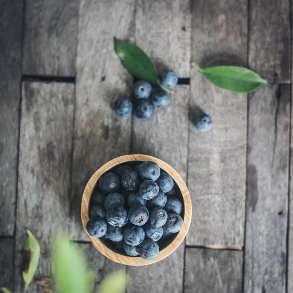 Prunes fraîches dans un bol en bois sur fond de bois ancien photo