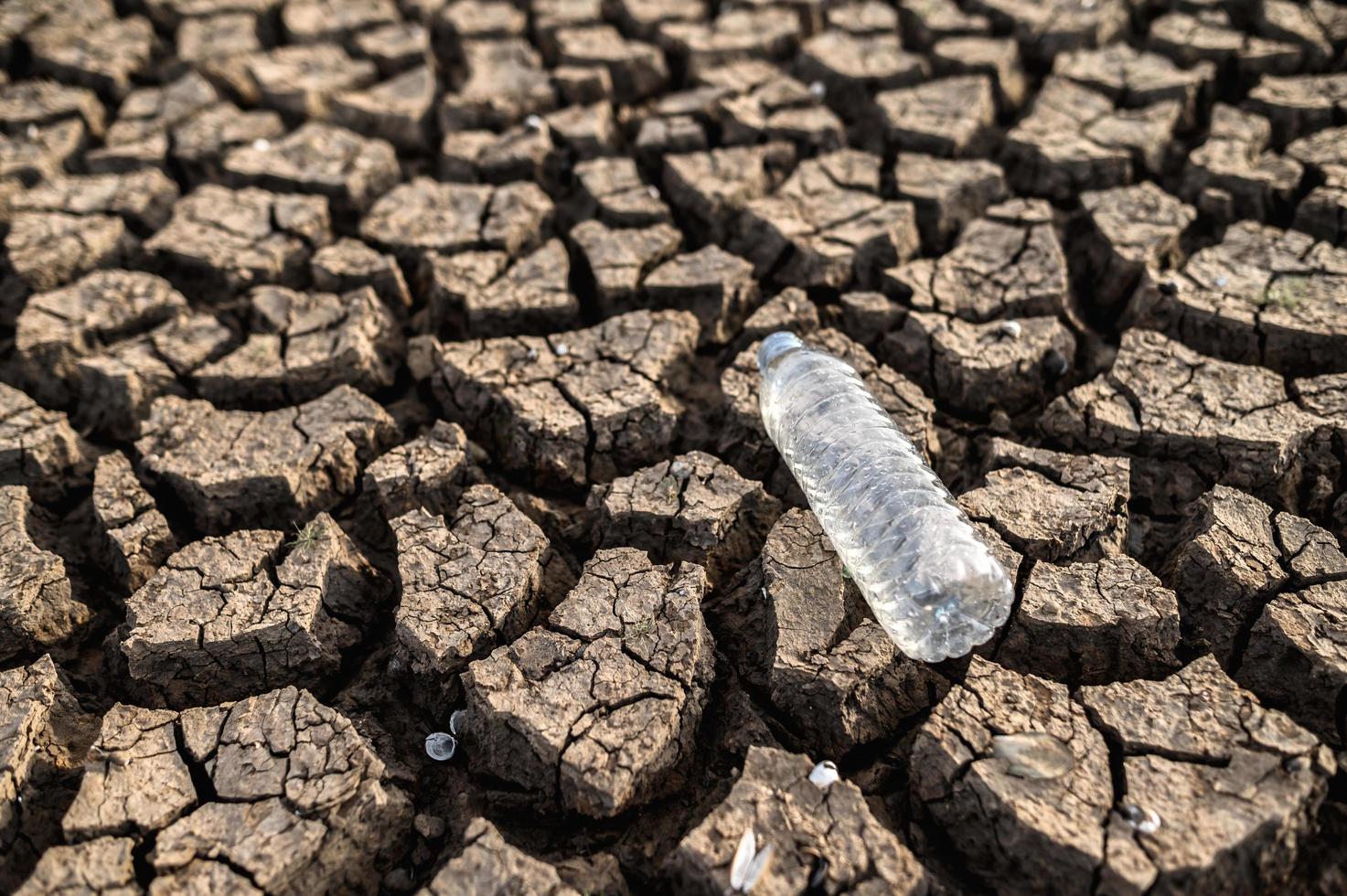 bouteille d'eau sur sol sec avec terre sèche photo