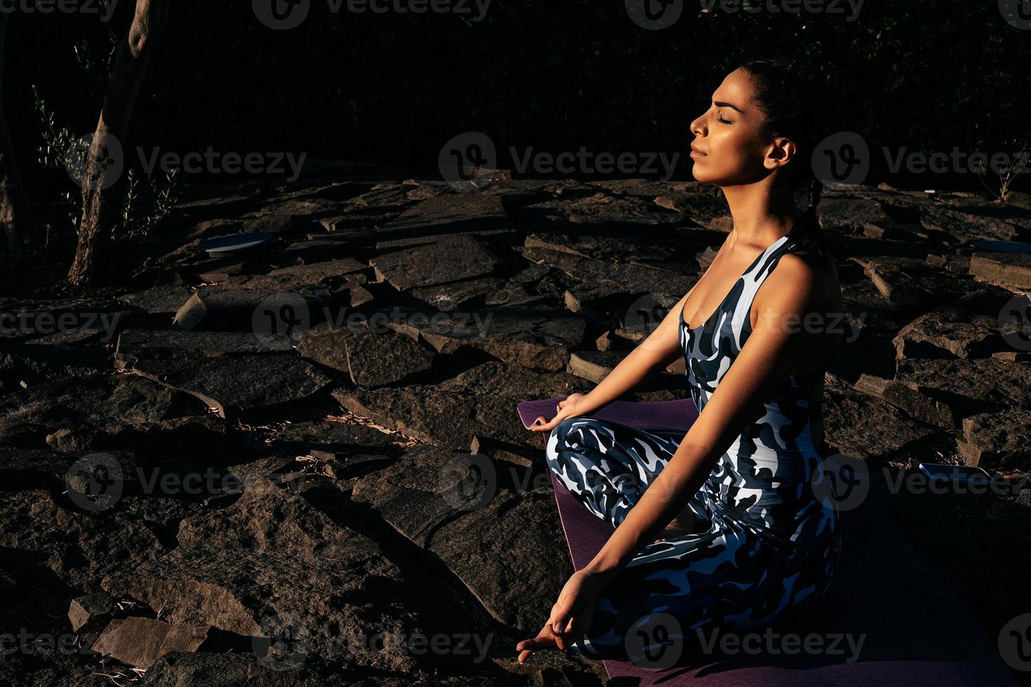 fille médite dans la nature est assis avec fermé yeux sur des pierres photo
