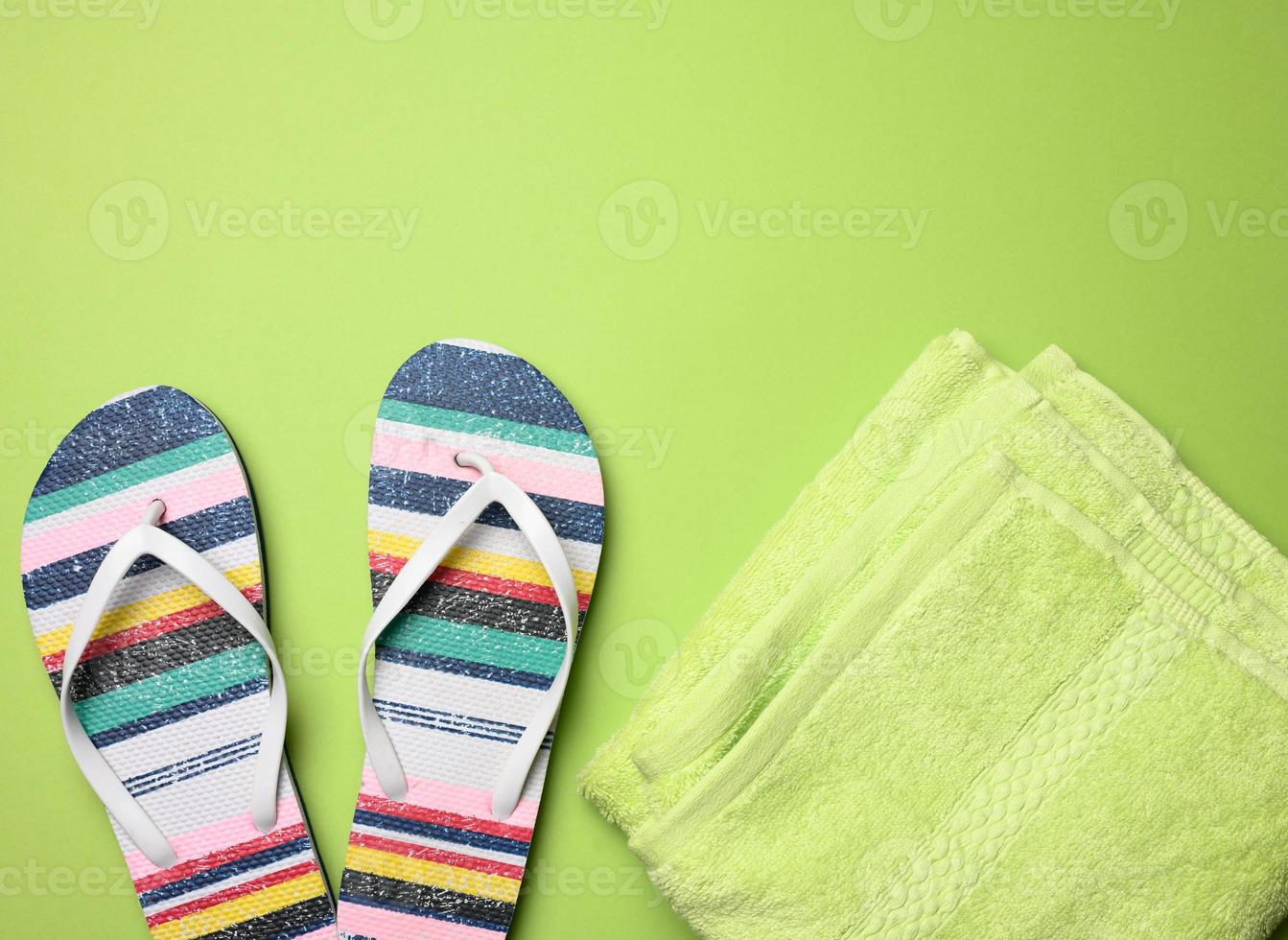 paire de femelle plage chaussons et une vert serviette sur une vert Contexte photo