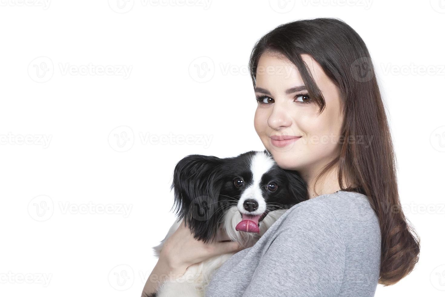 une charmant Jeune femme est étreindre sa papillon chiot et à la recherche dans le cummera. l'amour entre propriétaire et chien. isolé sur blanc Contexte. photo