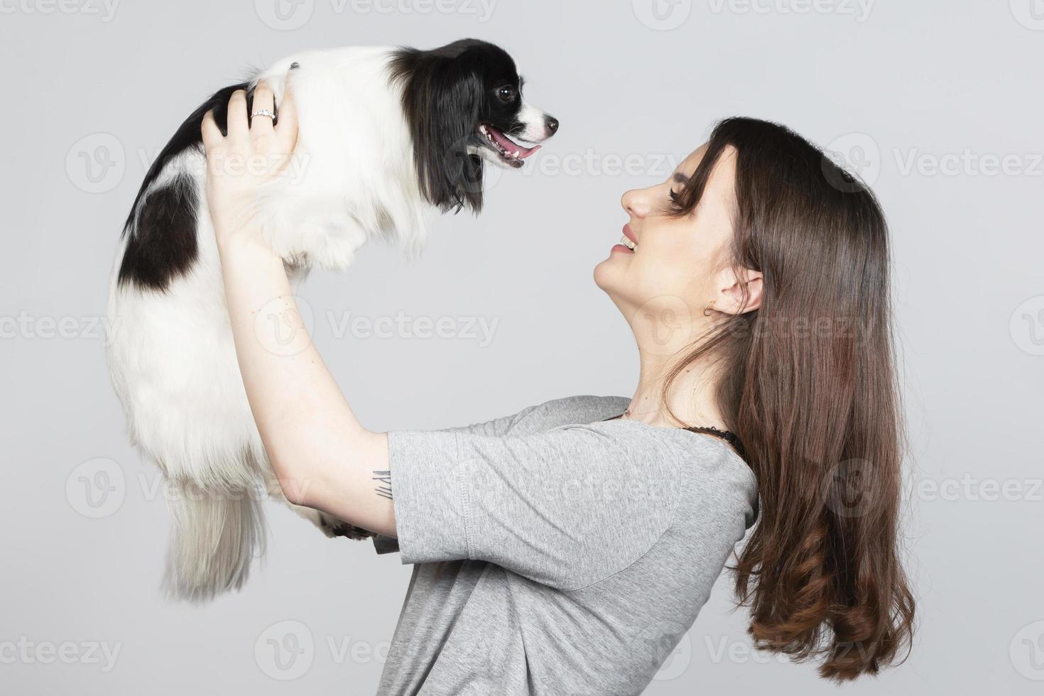 une mignonne Jeune femme est étreindre sa papillon chiot. l'amour entre propriétaire et chien. fille avec chien studio portrait. photo